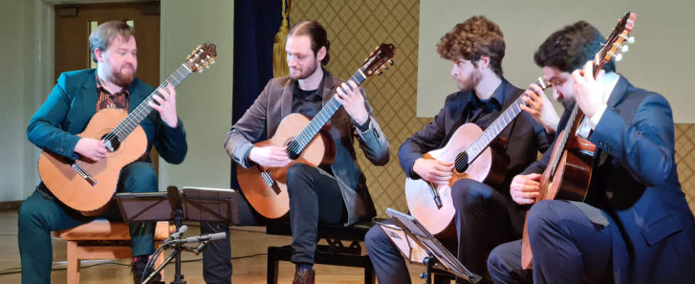 The quartet seate and playing their guitars at our concert