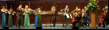 The orchestra at a performance. The violinists and violists are show playing standing up.