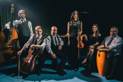 The six members of Classico Latino, posed against a dark background; most are holding their instruments.