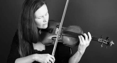A close-up of Zoë Beyers playing her violin. Her eyes are closed in concentration.