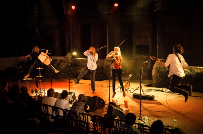 The quartet on stage in concert, all leaping into the air as they play their instruments